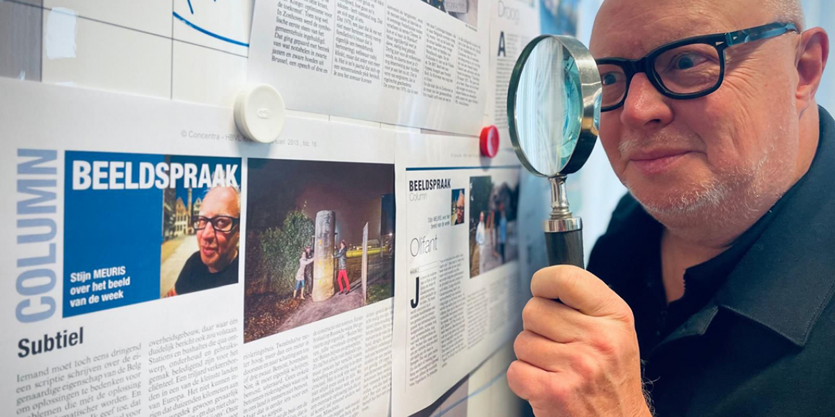 Stijn Meuris kijkt met vergrootglas naar krantenartikel