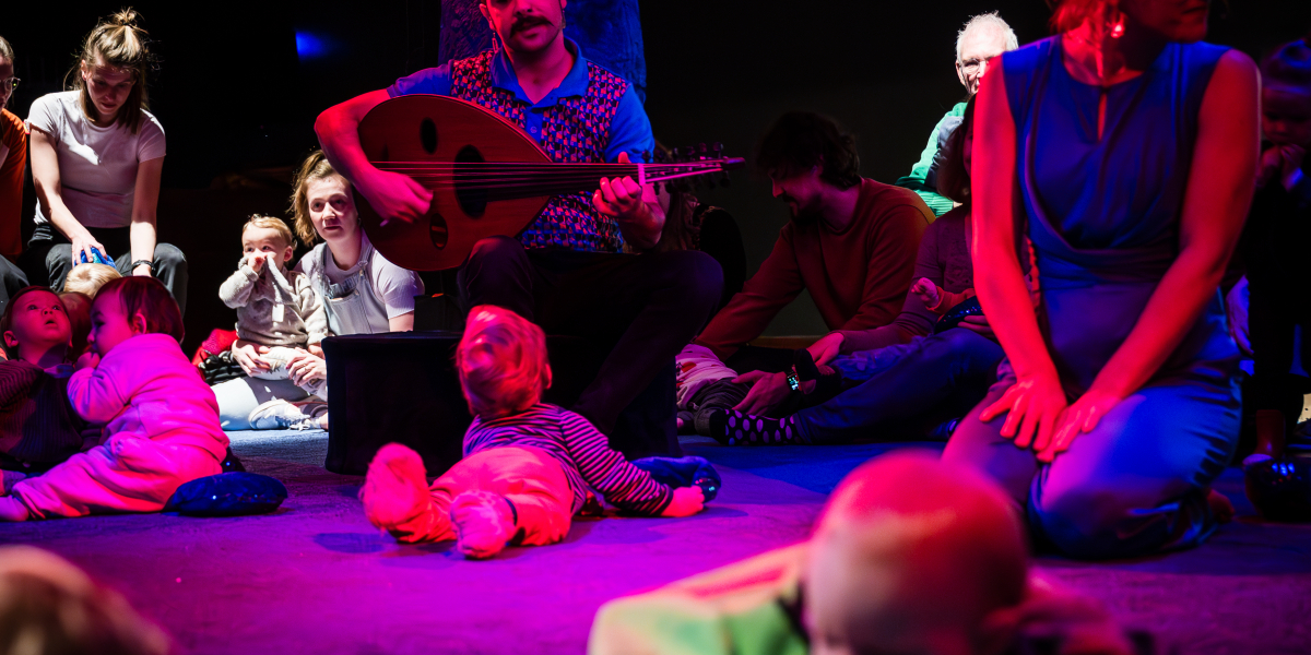 Volwassenen en kleine kinderen op een podium bij muzikanten